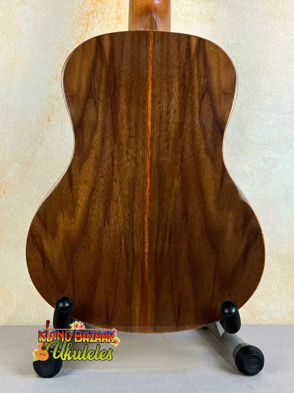 Wooden acoustic guitar with dark grain on stand, featuring Flight Sophia Soundwave Tenor