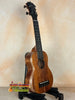 Wooden ukulele on black stand showcasing the Exquisite KoAloha KSM-00 Soprano Ukulele