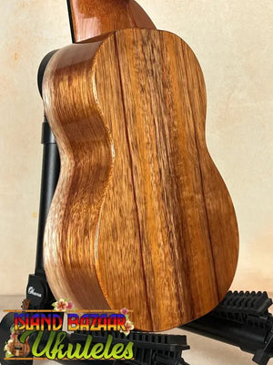 Wooden acoustic guitar with rich grain patterns beside the Exquisite KoAloha KSM-00 Soprano Ukulele