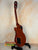 Brown acoustic guitar on black stand, showcasing Flight Centurion GT Tenor Electric Ukulele