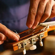 Guitar headstock being restrung with new strings.