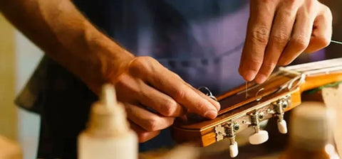 Hands tuning guitar strings with a focus on proper handling and professional maintenance.