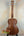 Wooden acoustic guitar with dark brown finish on black stand, Kala Archtop Tenor Ukulele