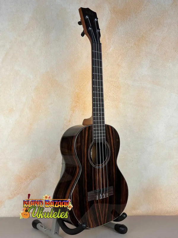 Dark wooden Kala Bocote Tenor Ukulele with striped grain on a stand, Premier Exotic Bocote