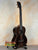 Dark wooden Kala Bocote Tenor Ukulele with striped grain on a stand, Premier Exotic Bocote