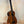 Brown acoustic-electric bass ukulele on a stand, showcasing Kala EM-FS Exotic Macawood Tenor