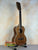 Wooden ukulele on stand, showcasing Kala KA-8 Eight-String Tenor in gloss mahogany finish