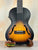 Sunburst-colored Archtop Tenor Ukulele on a stand, Kala KA-JTE-2TS with f-holes