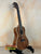 Wooden Kala KA-SA-C Acacia Concert Ukulele with four strings on a black stand