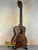 Wooden Kala KA-SA-T Acacia Tenor Ukulele with dark grain on a black stand