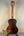 Wooden acoustic guitar with dark brown finish on stand, highlighting Kala KA-SA-T Acacia Tenor Ukulele