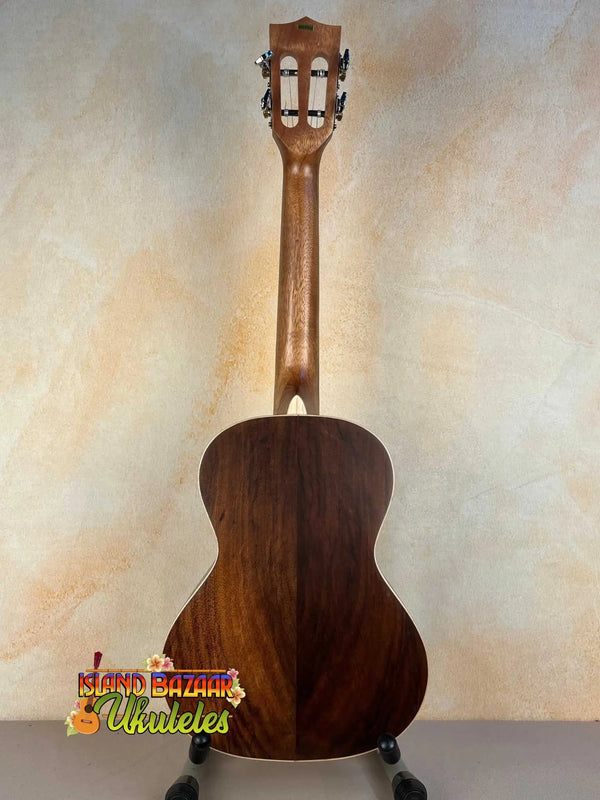 Wooden acoustic guitar with dark brown finish on stand, highlighting Kala KA-SA-T Acacia Tenor Ukulele