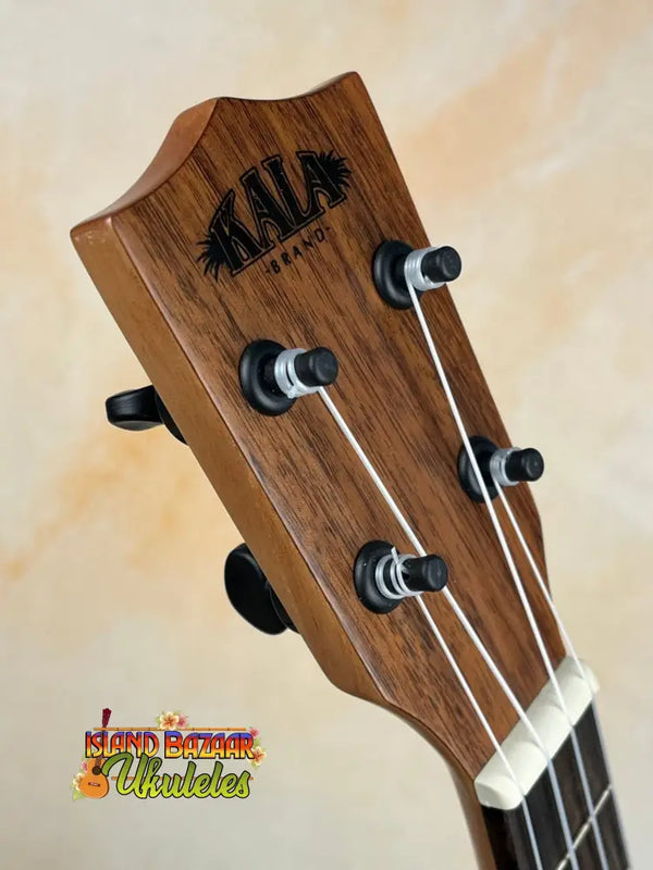 Wooden Kala KA-SCAC-T-CE Tenor Ukulele headstock with black tuning pegs and strings