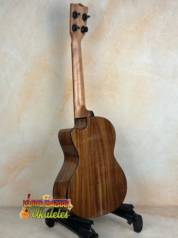 Wooden Kala KA-SCAC-T-CE Tenor Ukulele resting on a black stand for display