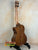 Wooden Kala KA-SCAC-T-CE Tenor Ukulele resting on a black stand for display