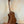 Wooden Kala KA-SMH-TG-CE Tenor Electric Ukulele on black stand showcasing solid mahogany