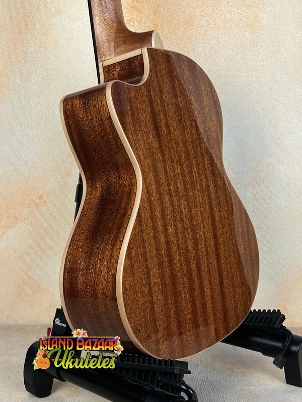 Acoustic guitar with brown wood grain on a stand, showcasing Kala KA-SMH-TG-CE Tenor Electric Ukulele