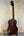 Dark brown wooden Kala KA-SMHT Tenor Ukulele on black stand showcasing classic design