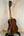 Wooden acoustic guitar on a stand near Kala SA-T Tenor Ukulele, showcasing rich design