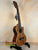 Wooden ukulele with a glossy finish on a stand, featuring the Kala SA-TE-C Tenor Electric