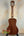 Wooden acoustic guitar with mahogany body on stand, showcasing Kala SMH-CG Concert Ukulele