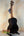 Black acoustic ukulele on stand showcasing Kala Solid Spruce Top Tenor Ukulele Striped Wood KA-SSEBY-T
