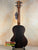 Dark wooden acoustic guitar with neck strap above Kala Solid Spruce Top Tenor Ukulele