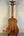 Wooden Kala U-Bass Nomad Acoustic-Electric Bass Ukulele on stand with black tuning pegs
