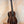 Dark wooden Kala UBASS-EBY-FSRW Striped Ebony Acoustic-Electric Bass Ukulele on black stand