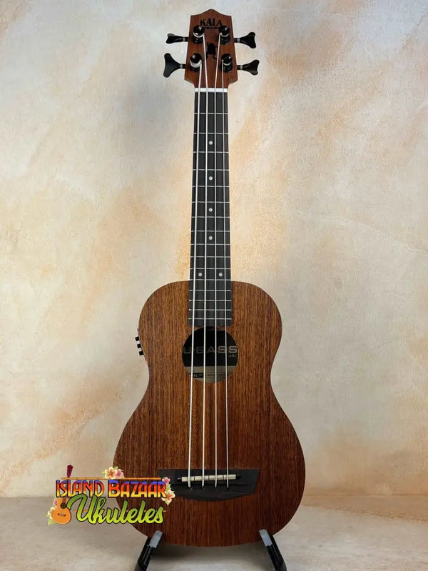 Brown wooden Kala Wanderer U-Bass Ukulele acoustic-electric on a black stand