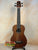 Brown wooden Kala Wanderer U-Bass Ukulele acoustic-electric on a black stand