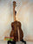 Wooden acoustic guitar with dark walnut patterns on a stand, Kanile’a HNS-T-PREM Tenor