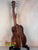 Wooden acoustic guitar on a black stand next to Kanile’a Honus Tenor Ukulele