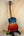 Blue and red Kanileʻa ʻILIKAI T Pro Tenor Ukulele on stand, perfect for island bazaar shoppers