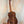 Wooden acoustic guitar on black stand featuring Kanile’a ISL-T Hawaiian Islands Tenor Ukulele