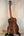 Wooden acoustic guitar on black stand featuring Kanile’a ISL-T Hawaiian Islands Tenor Ukulele