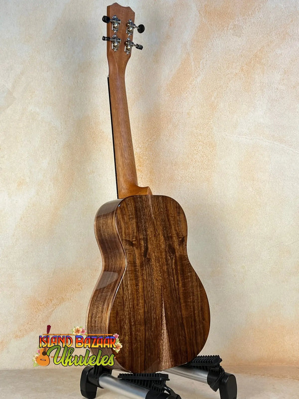 Wooden Kanile’a K-1 Tenor Ukulele with dark grain on black stand, deluxe koa wood design