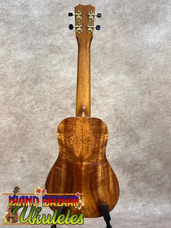 A kanileʻa koa core concert ukulele with a warm brown finish and intricate wood grain patterns in a deluxe gig bag