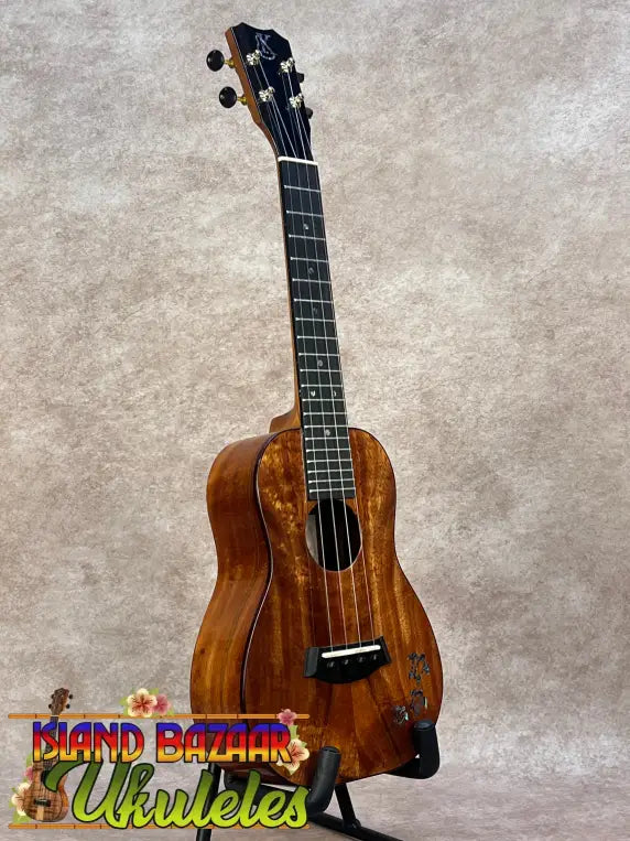 Kanileʻa koa core concert ukulele with glossy mahogany body and floral inlay featuring black tuning pegs