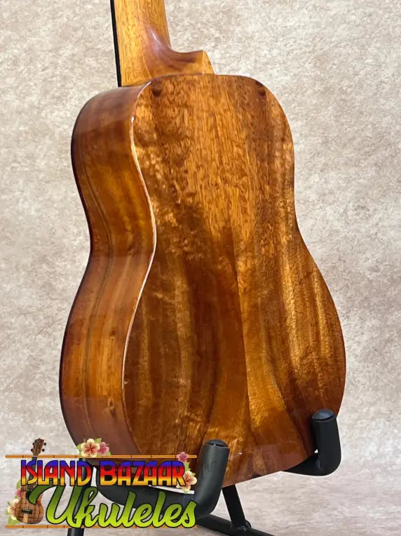 Kanileʻa koa core concert ukulele with deluxe gig bag in glossy amber wood featuring rich grain and elegant curves