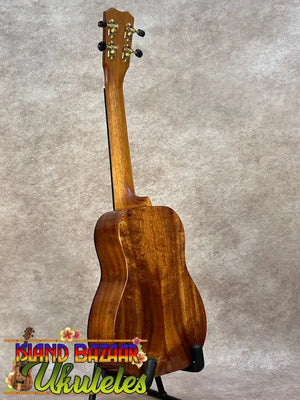 Kanileʻa koa core concert ukulele polished mahogany with golden tuning pegs on black stand for kanileʻa honus tenor fans