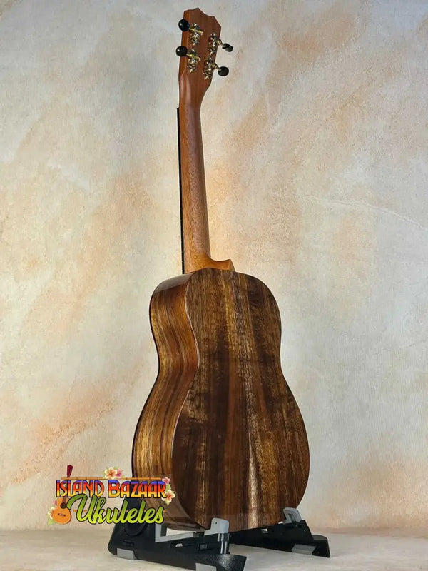 Wooden acoustic guitar on a black stand with Kanilea KPA-T Tenor Ukulele Hawaiian Koa