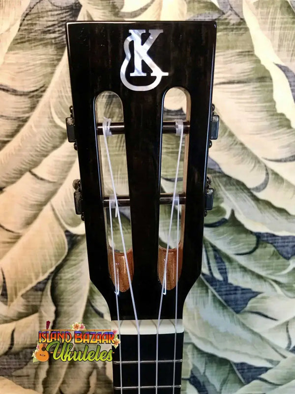 Guitar headstock of Kanile’a KSR Premium Tenor Ukulele displaying KC logo and tuning pegs