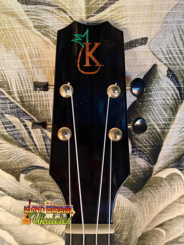 Guitar headstock with KC logo in orange and green on Kanile’a Pineapple Hawaiian Ukulele