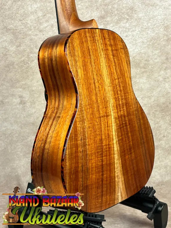 Richly grained wooden acoustic guitar with light binding, ideal for Kanile’a Super Tenor koa ukulele