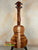 Wooden KoAloha Concert Hawaiian Ukulele in solid Hawaiian koa with rich grain on black stand