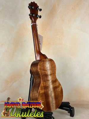 Wooden ukulele on a black stand, showcasing KoAloha Concert Hawaiian solid koa design