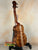 Wooden ukulele on a black stand, showcasing KoAloha Concert Hawaiian solid koa design