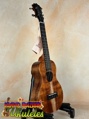 Wooden ukulele with dark grain on stand, showcasing KoAloha Concert Hawaiian craftsmanship
