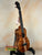 Wooden ukulele with dark grain on stand, showcasing KoAloha Concert Hawaiian craftsmanship